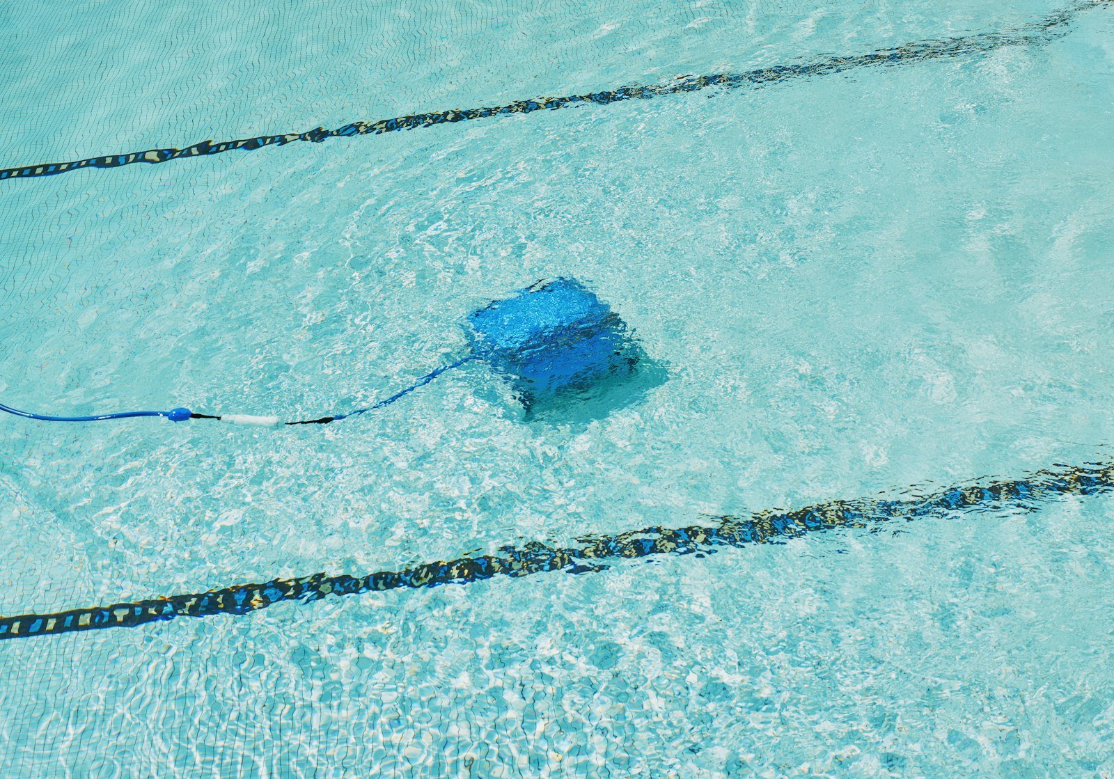 Robotic pool cleaner working along a swimming lane